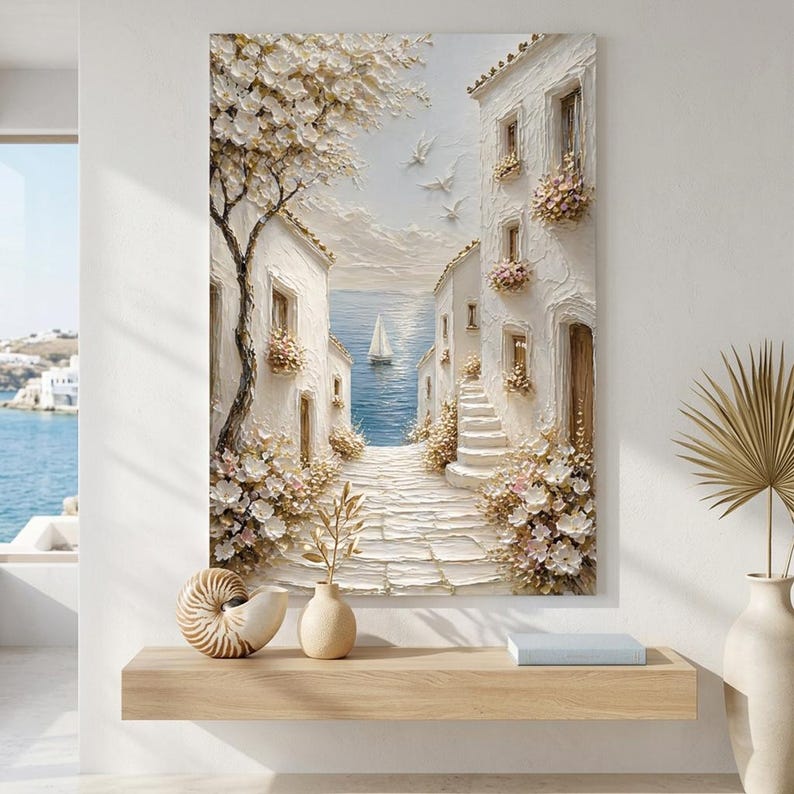 May include: A textured wall art painting depicting a coastal Mediterranean scene with white buildings, a stone path, and blooming flowers. A sailboat floats on the blue sea in the distance, while white birds fly in the sky above the bright, sunlit architecture.