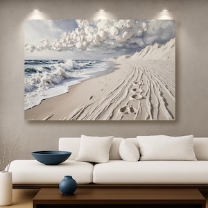 May include: A canvas print depicting a serene beach scene. The artwork features a white sandy beach, foamy ocean waves, and a cloudy sky. Footprints are visible in the sand, leading towards the horizon. The overall color palette is soft and natural.