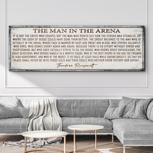May include: A rustic wooden sign with a white background and brown text. The sign features a quote by Theodore Roosevelt about the importance of action and courage. The quote reads: "It is not the critic who counts: not the man who points out how the strong man stumbles..."