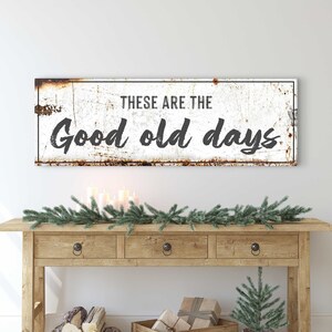 May include: White metal sign with a distressed, rusty look. The sign reads "These are the good old days".