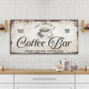 May include: A white and brown vintage-style sign with the text "The Smith's Coffee Bar" in a cursive font. The sign also includes the text "Dallas, Texas" and "Since 2018". The sign features a drawing of a cup of coffee with steam rising from it.