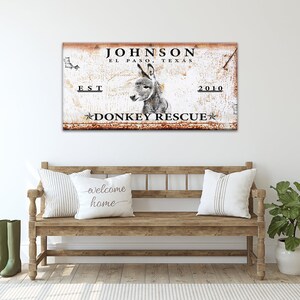 May include: Rustic metal sign with a donkey image and the text "JOHNSON EL PASO, TEXAS EST 2010 DONKEY RESCUE" in black lettering. The sign has a distressed, rusty look.