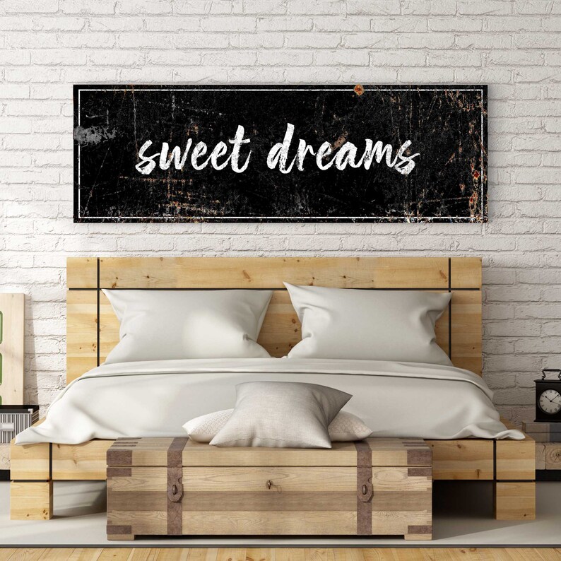 May include: A black and white sign with a distressed look and a white border. The sign says "sweet dreams" in a white cursive font.