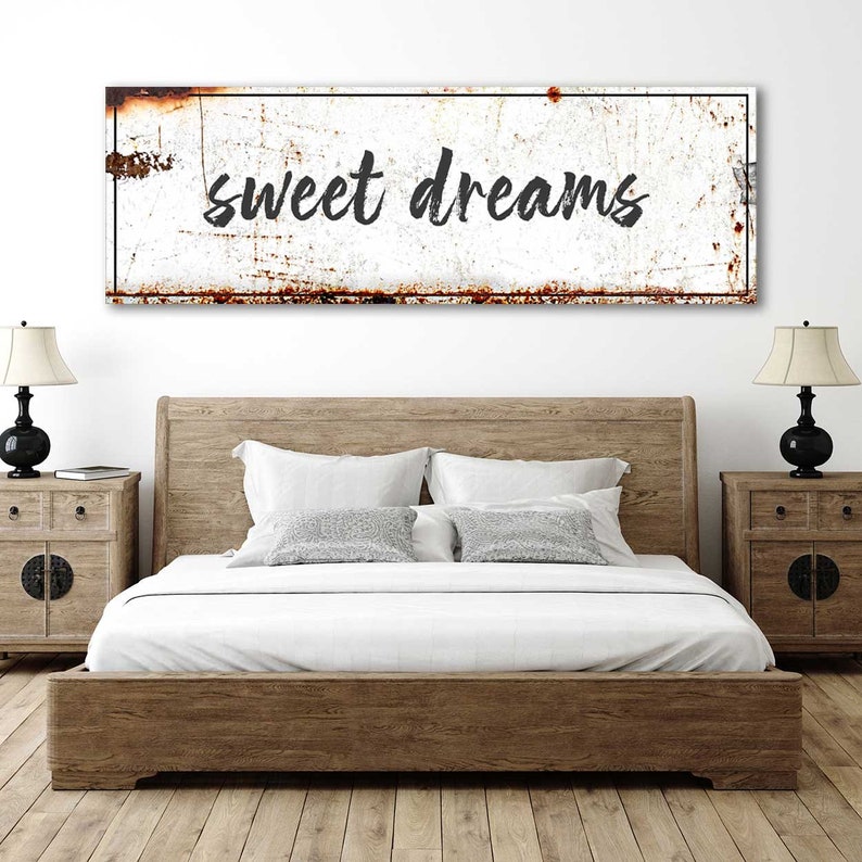May include: A white metal sign with a rusty texture and black border. The sign says "sweet dreams" in black cursive lettering.