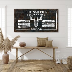 May include: A rustic wooden sign with the text "The Smith's Hunting Lodge" and a white silhouette of a deer head. The sign lists services offered, including ammunition, guide service, camp cooking, taxidermy, camp supplies, and guest cabins.