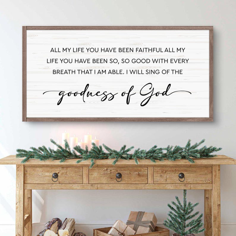 Puede incluir: Un letrero de madera enmarcado con el texto "ALL MY LIFE YOU HAVE BEEN FAITHFUL...goodness of God" en escritura negra. El letrero est&aacute; sobre una mesa de madera decorada con vegetaci&oacute;n, velas y un peque&ntilde;o &aacute;rbol de Navidad.