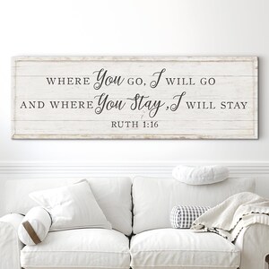K&ouml;nnte beinhalten: Ein rechteckiges Holzschild mit dem Text "WHERE You GO, I WILL GO AND WHERE You Stay, I WILL STAY RUTH 1:16" in schwarzer Schrift. Das Schild befindet sich &uuml;ber einem wei&szlig;en Sofa mit Kissen und einer Decke.