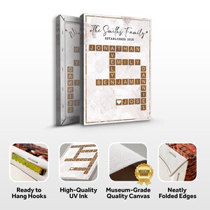 May include: A canvas print with a white marble background and a crossword puzzle featuring the names "Jonathan", "Emily", "Benjamin", and "Jose" in brown wooden letter tiles. The text "The Smiths Family Established 2018" is at the top of the print. The print has a gold frame and is ready to hang with hooks.