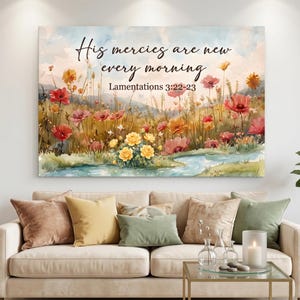 May include: A rectangular wall art print featuring a watercolor landscape of a wildflower meadow with red, yellow, and pink flowers near a blue stream. The text reads: His mercies are new every morning, Lamentations 3:22-23 in black script.