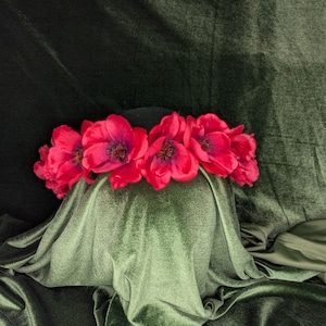 May include: A black hat with a crown of bright red poppy flowers.