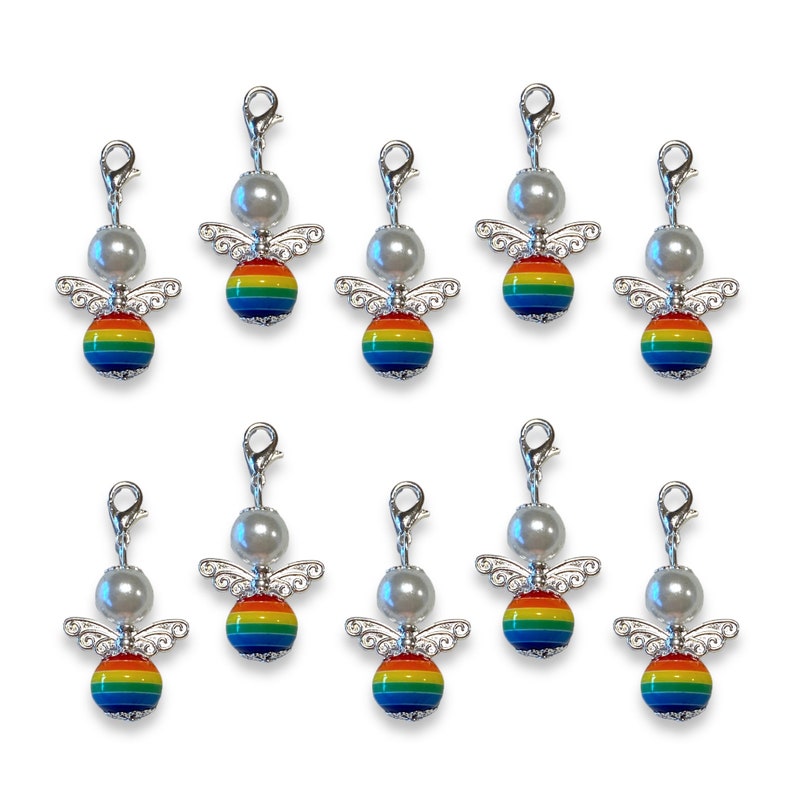 May include: Ten silver angel charms with rainbow coloured wings and a white pearl bead. Each charm has a silver clip for attaching to a bag, purse, or other item.