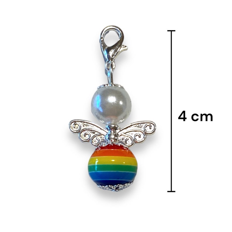 May include: A silver charm featuring a rainbow-coloured bead and a white pearl bead. The charm is shaped like an angel with silver wings. The charm is 4 cm long.