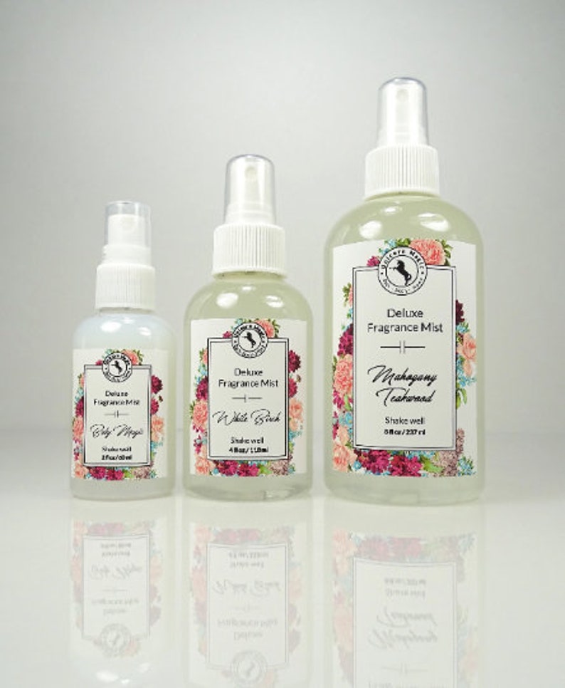 May include: Three glass bottles of fragrance mist with white spray tops and floral labels. The bottles are labeled "Deluxe Fragrance Mist" with the scents "Baby Magic", "White Birch", and "Mahogany Teakwood".