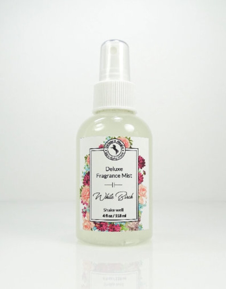 May include: A clear glass bottle with a white spray top and a white label. The label has a floral design and the text "Deluxe Fragrance Mist - White Birch - Shake well 4 fl oz/118 ml".