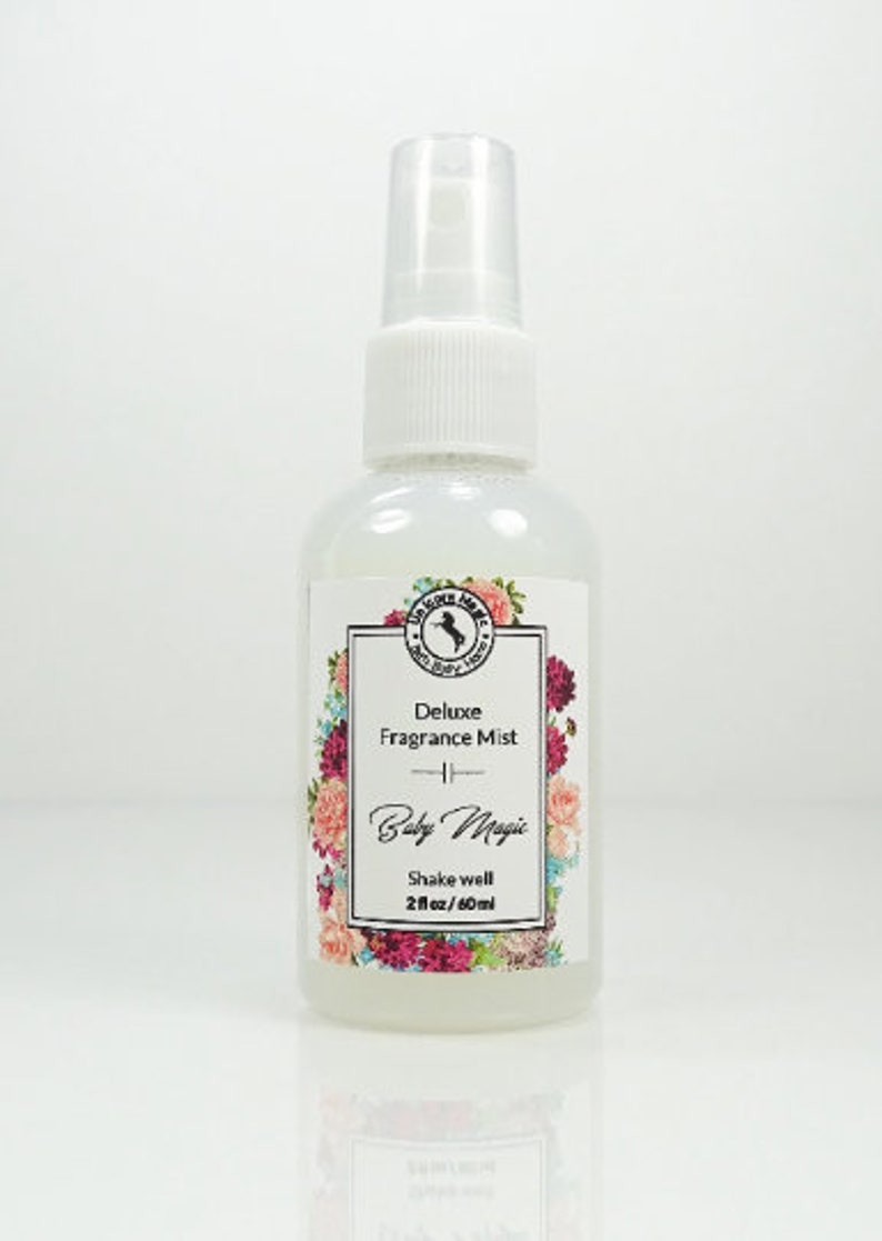 May include: A clear plastic bottle with a white pump top and a white label. The label has a floral design and the text "Deluxe Fragrance Mist - Baby Magic - Shake well 2 fl oz/60 ml".