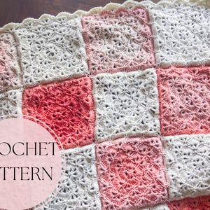 Puede incluir: Una manta de ganchillo hecha a mano con un diseño de patchwork. Los cuadrados son blancos, rosas y rojos. El texto "CROCHET PATTERN" está en un círculo rosa en la esquina inferior izquierda. Los bordes tienen un ribete festoneado.