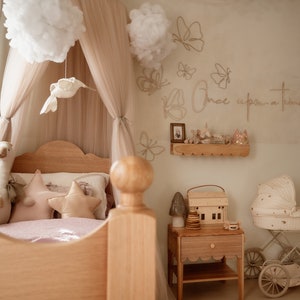 May include: A child's bedroom featuring a wooden bed with a beige canopy, a swan plush, and star-shaped pillows. The wall displays butterfly outlines and the text "Once upon a time" above a wooden shelf, a nightstand, and a vintage-style doll carriage.