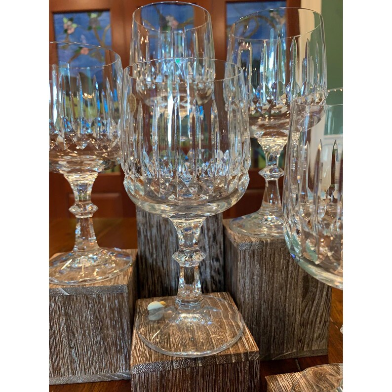 May include: Set of six clear glass wine glasses with a cut crystal design. The glasses are displayed on wooden blocks.