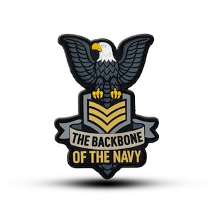 Puede incluir: Un emblema negro, gris y amarillo con un águila con las alas extendidas, posada sobre una pancarta. La pancarta dice "THE BACKBONE OF THE NAVY". El águila tiene la cabeza blanca y el pico y las garras amarillas.