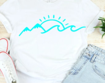 May include: A white t-shirt with a turquoise blue graphic of a sun setting behind mountains and waves.