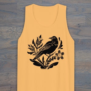 May include: A yellow tank top with a black silhouette of a bird perched on a branch with flowers. The design is in a folk art style.