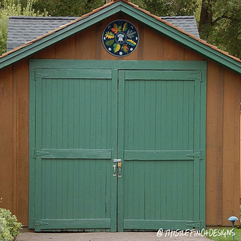 Puede incluir: Una puerta de garaje de madera verde con dos paneles y una cerradura. La puerta est&aacute; en un edificio con un techo de madera marr&oacute;n y un dise&ntilde;o circular sobre la puerta.