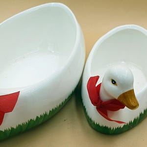 May include: Three white ceramic goose-shaped bowls with red and green accents. The bowls are different sizes and have a glossy finish.