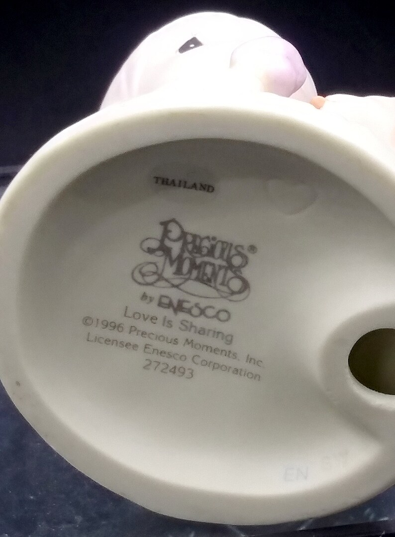 以下が含まれることがあります： 手をつないでいるカップルの白い磁器の置物で、台座に「Precious Moments」と「Love Is Sharing」の文字が書かれています。この置物はタイ製で、272493という番号が付けられています。