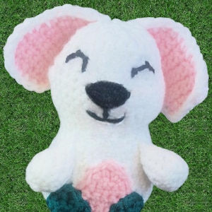 May include: A white crocheted stuffed animal with pink ears and a pink and green crocheted bottom. The animal has a black nose and smiling mouth.