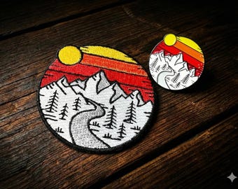 Kombination av emaljnål och märke på Mountain Sunset