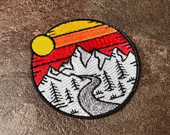 Broderad lapp med bergssolnedgång