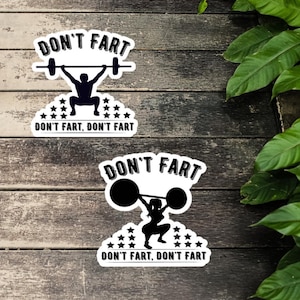 May include: Two white stickers with the text "DON'T FART" above a weightlifter silhouette. The bottom of the stickers read "DON'T FART, DON'T FART" with star accents. One sticker features a barbell, the other a round weight.