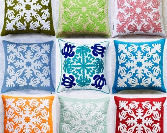May include: Ten colorful throw pillows with a white geometric pattern. The pillows are arranged in two rows of five. The pillows are made of fabric and have a quilted design.