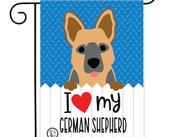 May include: A blue and white garden flag with a cartoon German Shepherd dog peeking over a white picket fence. The flag says "I love my German Shepherd" with a red heart.