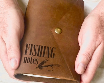 May include: A brown leather journal with the words "FISHING notes" and a fly fishing lure engraved on the front cover.