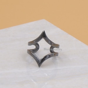 Op de afbeelding: Een zwarte metalen ring met een geometrisch ontwerp. De ring is aan één kant open en heeft een puntige vorm.