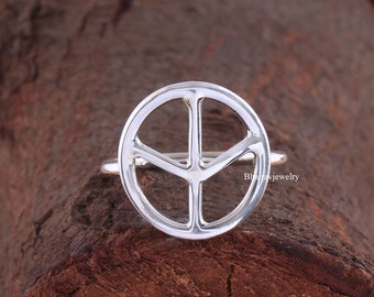 Könnte beinhalten: Ein silberner Friedenszeichenring. Der Ring besteht aus einem einzigen Stück Metall und hat ein schlichtes, minimalistisches Design.
