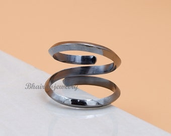 May include: A black metal ring with a double spiral design. The ring is made of a thick wire and has a smooth finish.