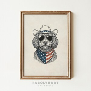 May include: A framed art print featuring a dog wearing a cowboy hat, sunglasses, and a bandana with an American flag design. The dog has curly fur and is centered in the frame. The frame is gold-colored, and the print has the text "FABOLYNART ART PRINTS" at the bottom.