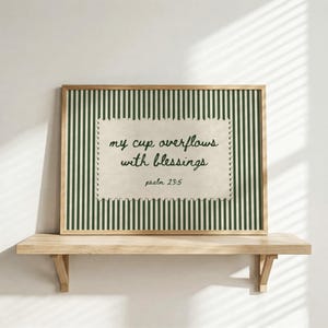 Framed art with green stripes and text "my cup overflows with blessings psalm 23:5".