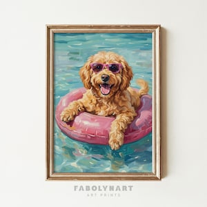 May include: A framed art print depicts a golden doodle dog wearing pink sunglasses and floating in a pink inner tube in a pool. The dog is smiling with its tongue out. The water is a light blue color. The frame is gold. The text "FABOLYNART ART PRINTS" is at the bottom.