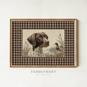 May include: Framed art print featuring a detailed illustration of a German Shorthaired Pointer dog and a duck in a natural setting. The artwork is set within a gold frame with a brown and white checkered border. The print is labeled "FABOLYNART ART PRINTS".