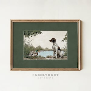 May include: Framed art print featuring a hunting dog and a duck near a body of water. The dog is brown and white, and the duck has green and brown feathers. The print is in a gold frame with the text "FABOLYNART ART PRINTS" at the bottom.