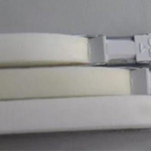 May include: Three white curtain rods with attached brackets. The rods have a rectangular shape with a foam-like material. The brackets have the text "KH388-1 330" printed on them. The rods are stacked on top of each other.