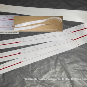 May include: White needle position indicators with red markings and text. The image includes multiple strips, with a close-up of a smaller indicator and text that reads "(2) 3 Needle Position Indicator for Brother KnitKing Bulky 9mm KH260 KH270 KH230".