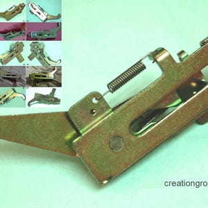 May include: A metal appliance part with a spring and lever arm. The part is gold-colored and has a rectangular body with a curved arm. Several smaller images of similar parts are in the upper left corner. The text "creationgroups" is in the lower right corner.