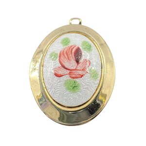 May include: Oval gold-tone pendant with a painted floral design. The pendant features a white background with a red and brown flower and green accents. The pendant has a loop at the top for a chain.