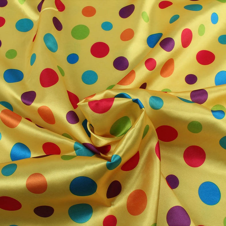 May include: Yellow satin fabric with a pattern of colorful polka dots in red, blue, green, orange, and purple. The fabric is gathered and folded, creating a textured appearance. Ideal for crafting or costume design.