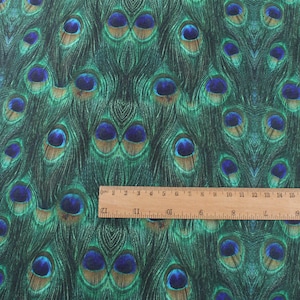 May include: Close-up of a fabric with a repeating pattern of peacock feathers. The feathers are green, blue, and brown with a metallic sheen. The fabric is textured and has a slight sheen.