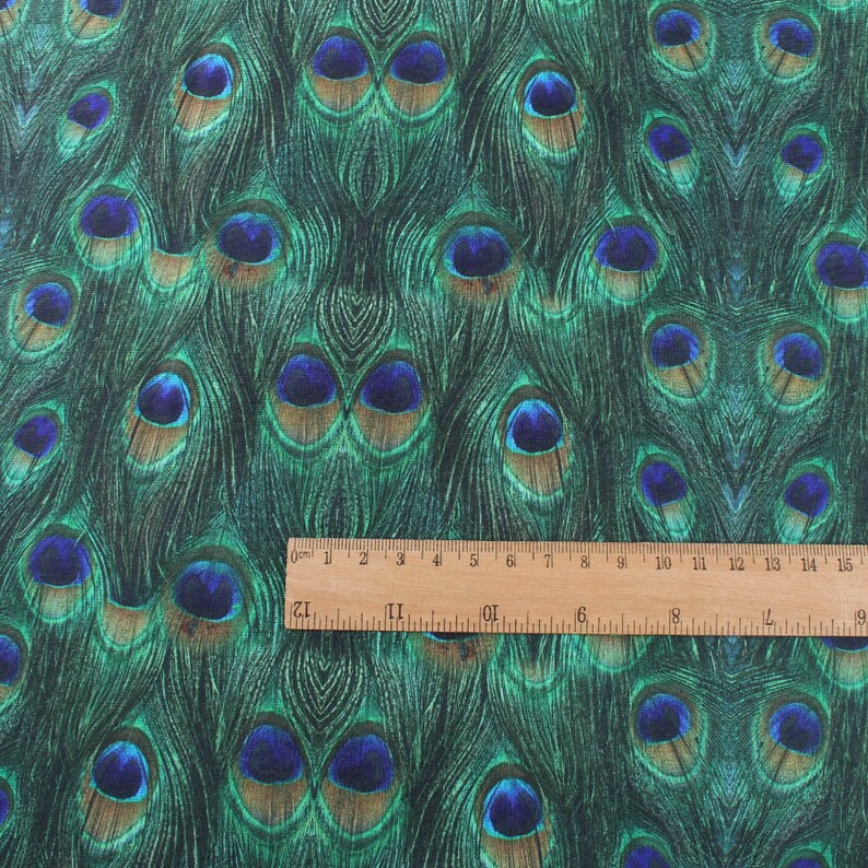 May include: Close-up of a fabric with a repeating pattern of peacock feathers. The feathers are green, blue, and brown with a metallic sheen. The fabric is textured and has a slight sheen.